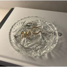 two gold and silver rings on a clear glass plate next to a white box with the lid open