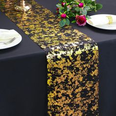 a black table cloth with yellow and red speckles on it, along with white plates