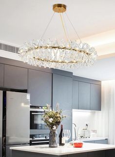 a chandelier hanging from the ceiling in a kitchen with gray cabinets and white countertops