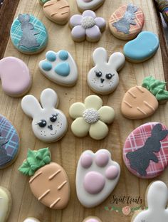 decorated cookies are arranged on a wooden tray with bunny ears, carrots and rabbits