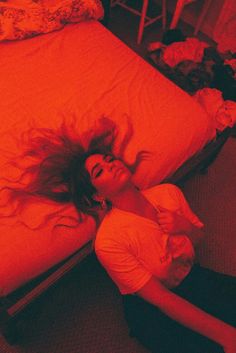 a woman laying on top of a bed under a red light