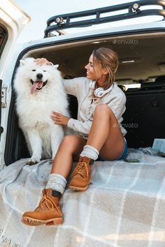 a woman sitting in the back of a truck with her dog