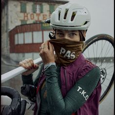 a woman wearing a helmet and holding a bike in front of her face with the word pass written on it