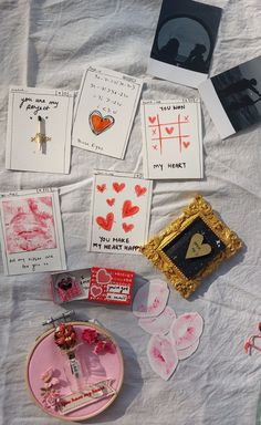 some cards and pictures are laying on a bed with white sheets, scissors, and other items