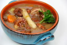 a blue bowl filled with beans, carrots and other foods on top of a white table