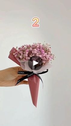 a person holding a bouquet of flowers with the number 2 on it's side