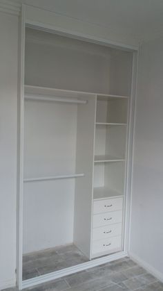 an empty walk in closet with white shelves and drawers on either side of the closet door