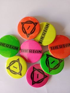 six different colored buttons with the word theatre on them in black and red, yellow, green, orange, and blue