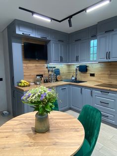 a kitchen with grey cabinets and green chairs around a round wooden table in the center