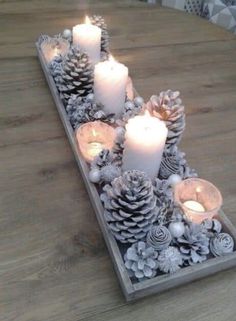 some candles are sitting on a table with pine cones