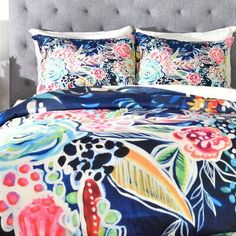 a bed with blue and pink floral comforter set on it's headboard