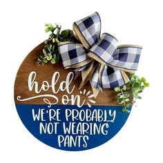 a wooden sign that says hold on we're probably not wearing pants with a bow