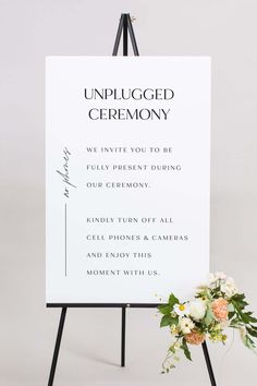 an unplugged ceremony sign with flowers on it next to a flower arrangement