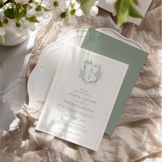 the wedding stationery is laid out on a table with white flowers and greenery