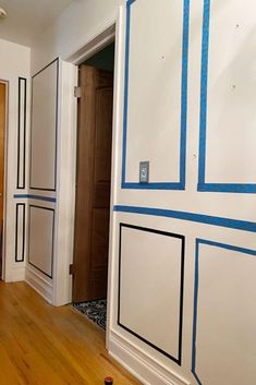 an empty room with blue tape on the walls and wood flooring in front of it