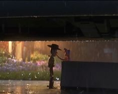 a person standing in the rain with a hat on and holding an umbrella over their head