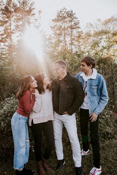 a group of people standing next to each other in front of some trees and bushes