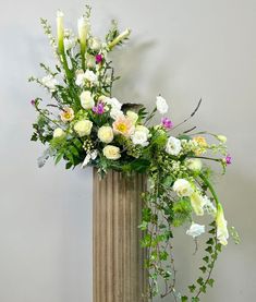 a tall vase with flowers and greenery in it