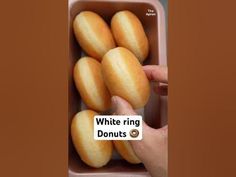 a person holding a container filled with donuts in it's left hand and the words white ring donuts above them