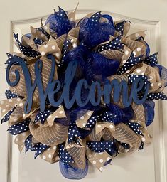 a welcome wreath with polka dots and blue ribbon hanging on the front door for someone's house