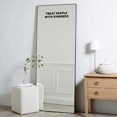 a mirror sitting on top of a wooden floor next to a white table and chair