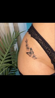 a woman's stomach with butterflies and leaves tattoo on the side of her belly