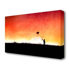 a person holding a heart shaped balloon on top of a grass covered field at sunset