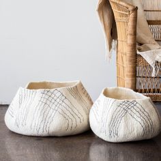 two white slippers sitting on top of a wooden floor next to a wicker basket