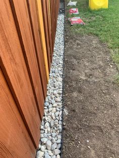 the side of a wooden fence with rocks on it