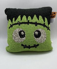 a green and black pillow with eyes on it