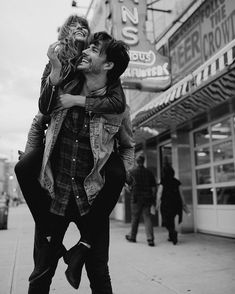 black and white photograph of two people hugging on the sidewalk in front of a movie theater