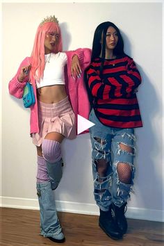 two women standing next to each other in front of a wall with ripped jeans and pink hair