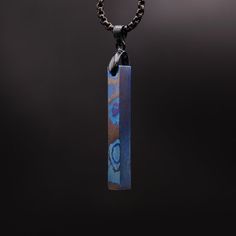 a necklace with a wooden pendant hanging from it's side on a black background