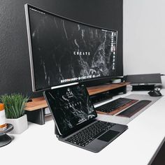 a laptop computer sitting on top of a white desk next to a monitor and keyboard