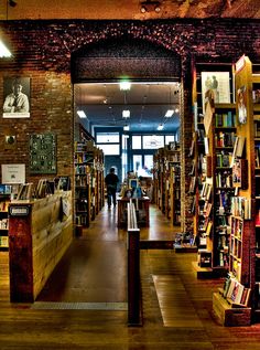 an open book store with lots of books on shelves and people walking through the doorway