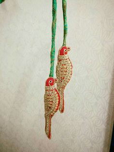 two red birds hanging from a string on a white wall next to a green cord