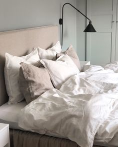 an unmade bed with white sheets and pillows