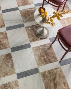 two chairs and a table on a checkered tile floor with flowers in vases