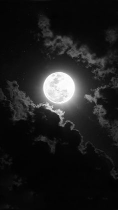 the full moon is shining brightly in the dark night sky with fluffy clouds around it