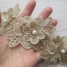 two handmade flower brooches with pearls in the middle and one being held by someone's hand