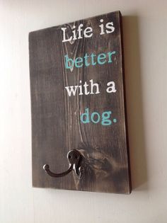 a wooden sign with the words life is better with a dog hanging from it's hook