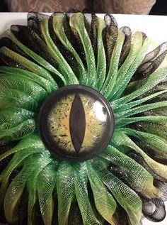 a close up of a green and black wreath with an eye