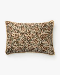 an embroidered pillow on a white wall with a brown and blue floral design in the middle