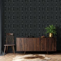 a wooden cabinet sitting next to a chair on top of a hard wood floor in front of a black wall