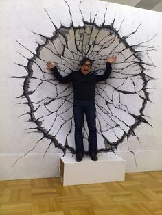 a man is standing in front of a large piece of art that looks like a tree trunk