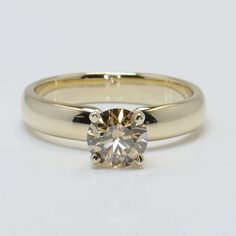 a yellow gold engagement ring with a round diamond