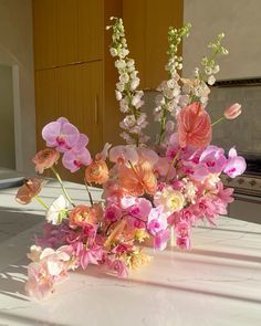 a vase filled with pink and white flowers sitting on top of a kitchen counter next to an oven