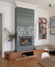 a living room filled with furniture and a fire place next to a wall mounted book shelf