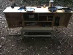 an outdoor kitchen with pots and pans on the counter top, in the woods