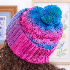 a woman wearing a multicolored knitted hat with pom - pom